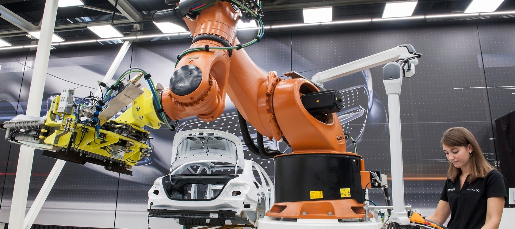 Einbau der Batterie in ein Hybridfahrzeug. Durch Mensch-Roboter-Kooperation (MRK) und den Einsatz eines Fahrerlosen Transportfahrzeugs (FTF) wird die Montage flexibler.