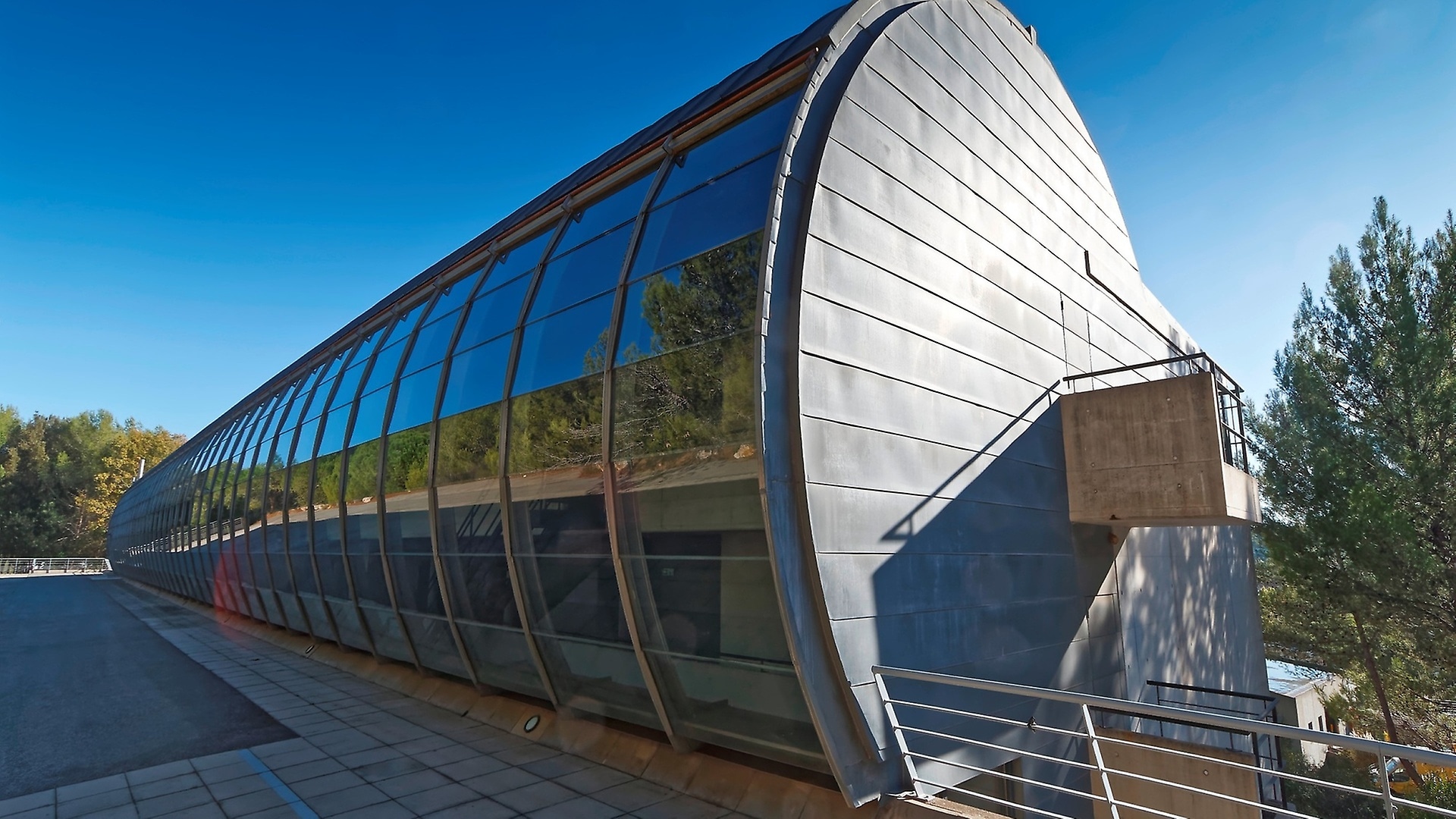 Der 50 Meter lange und 20 Meter breite Bau in Form eines Zylinders liegt eingebettet in einem Pinienwald; Beton und Glas dominieren in der klaren Architektur des Gebäudes.