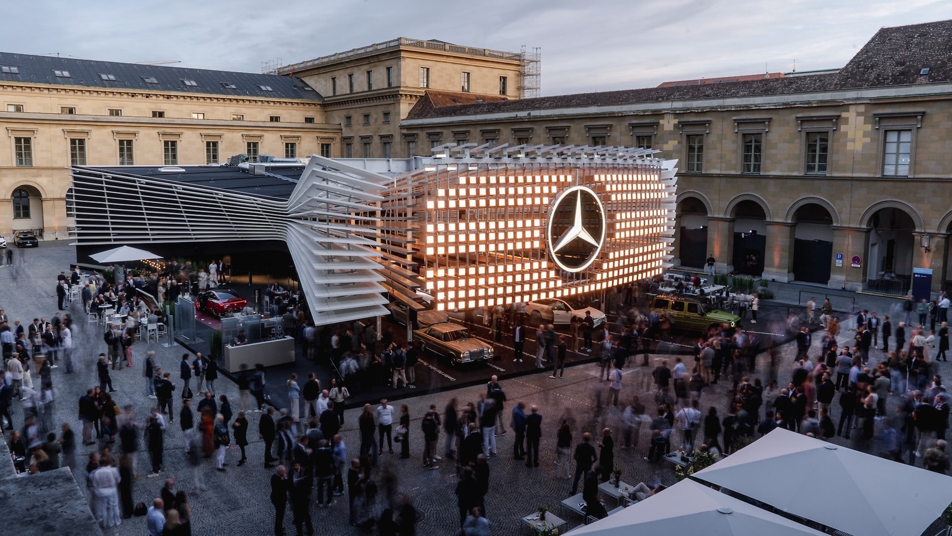 The Mercedes-Benz trade fair stand at the IAA 2025. The striking illuminated sculpture in the centre of the Apothekenhof of the Munich Residence’s courtyard represents the brand’s new iconic grille on a grand scale. 