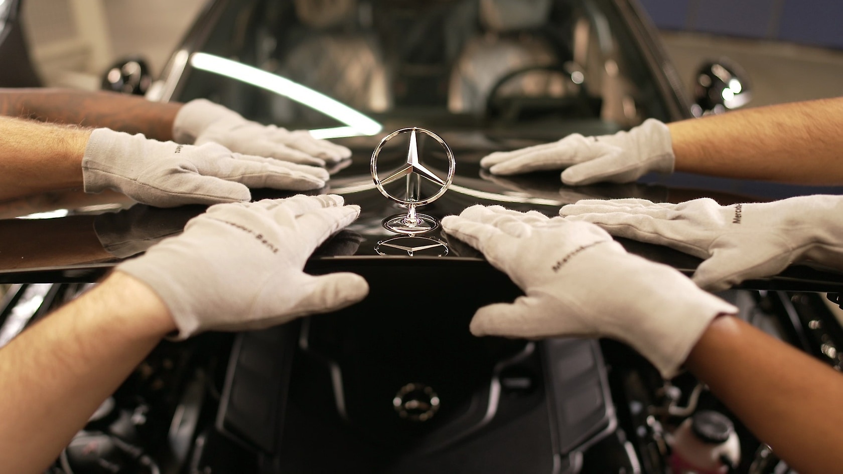 Hands with Mercedes star on the bonnet.