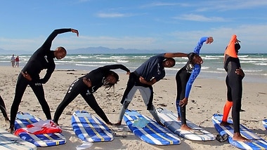 Beim Surfprojekt „Waves for Change“ in Kapstadt haben die Kids Spaß auf dem Brett und werden gleichzeitig präventiv über HIV aufgeklärt. 